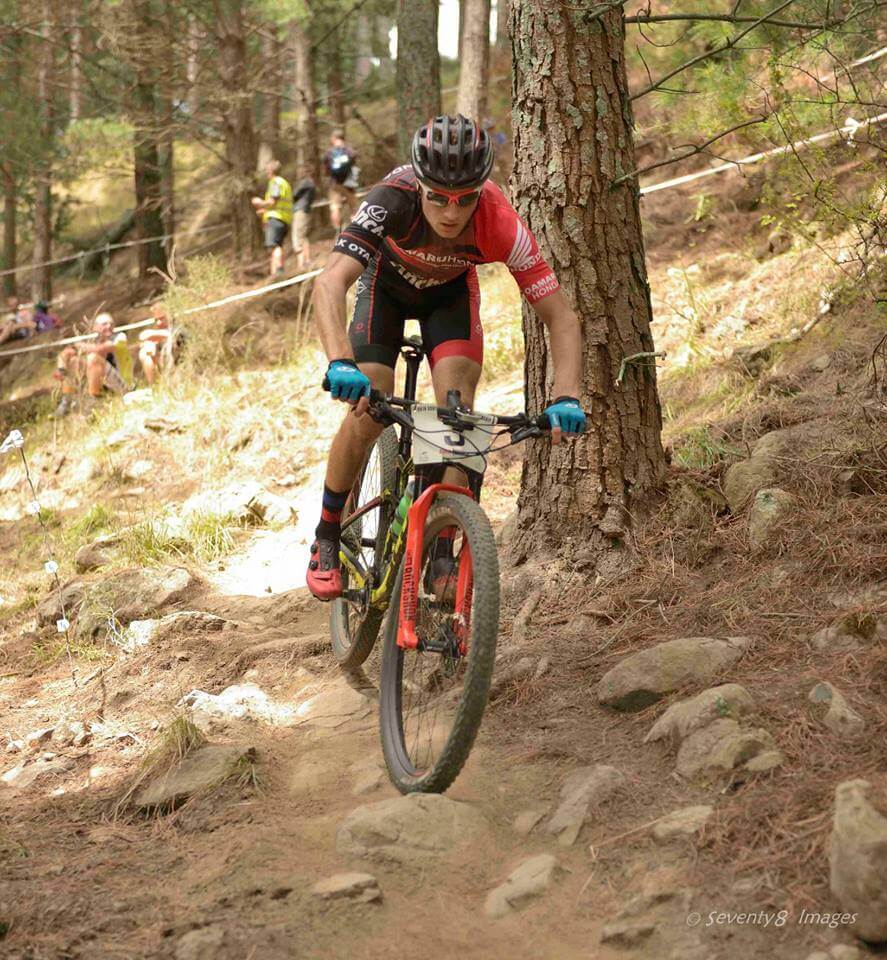 A man is riding a bike down a trail in the woods.