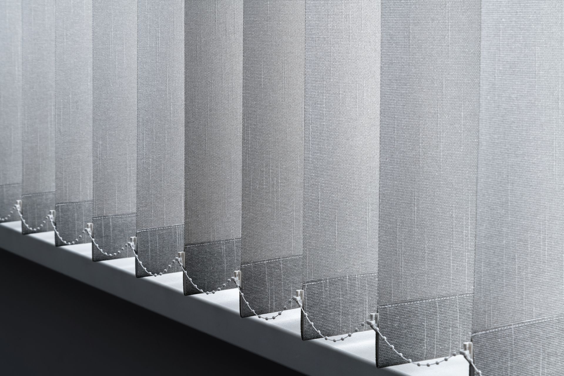 A close up of a row of vertical blinds on a window.