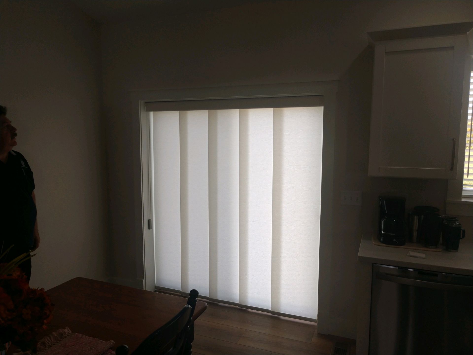 A laptop computer is displaying a living room with three windows and blinds.