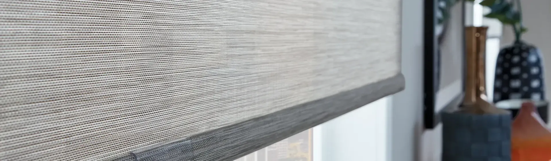 A close up of a roller blind on a window in a living room.