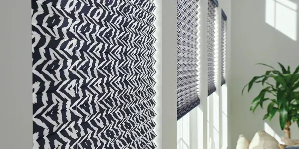 A living room with a couch and a plant and a black and white pattern on the wall.