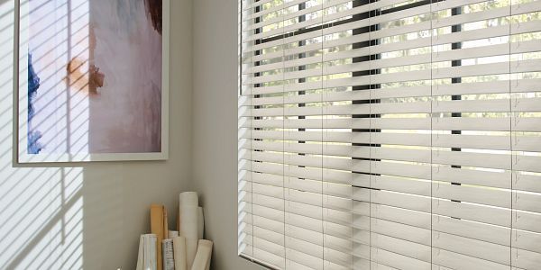 A room with white blinds and a picture on the wall.