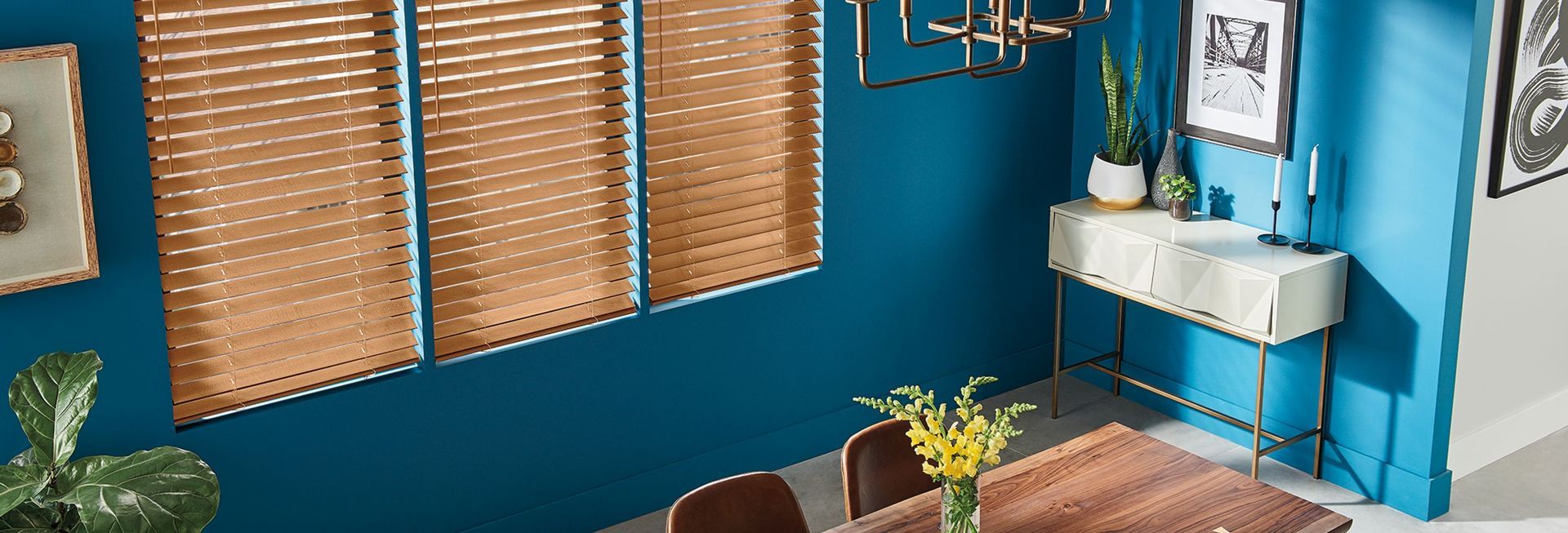 A dining room with blue walls , wooden blinds , a table and chairs.