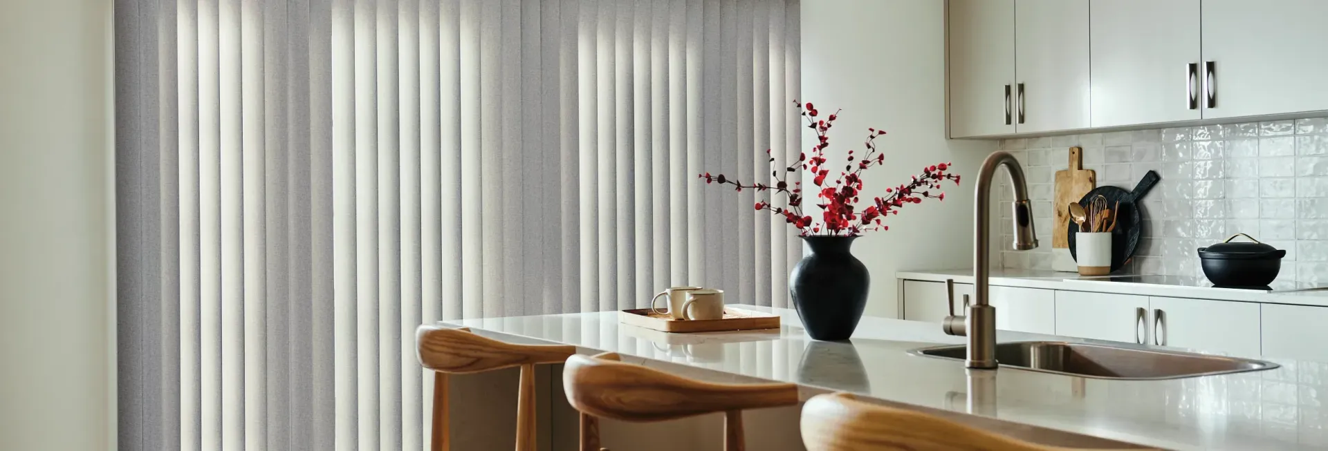 A kitchen with vertical blinds and a vase of flowers on the counter.