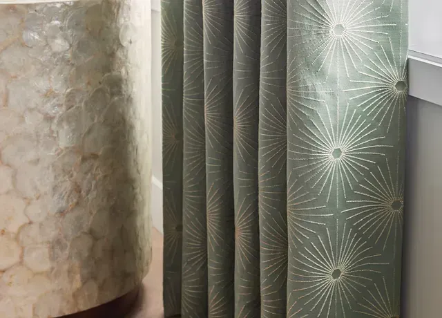A close up of a row of curtains in a bathroom next to a sink.