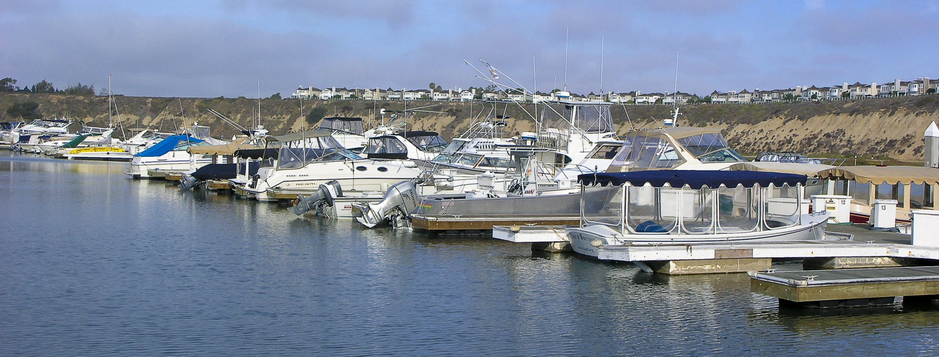 Boats slipped in marina with houses on bluffs in the background