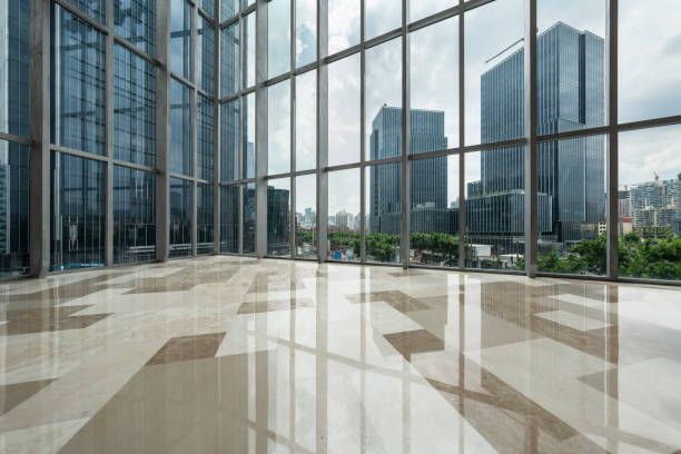 An empty office building with a lot of windows and a marble floor.