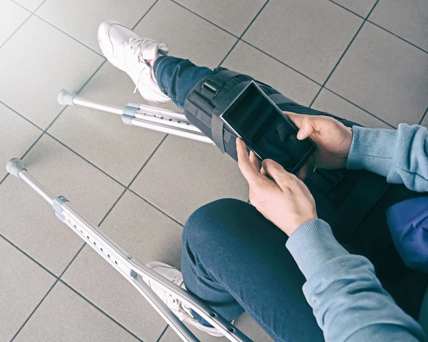 A person with crutches is using a cell phone