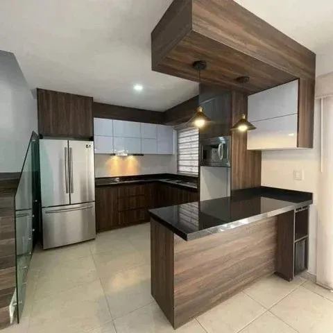 Modern kitchen with wood cabinets, island with black countertop, stainless steel appliances, and white and gray cabinets.