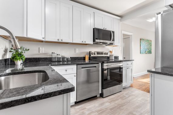 Exterior of a motel; two-story building with blue trim and doors, white siding, blue sky.