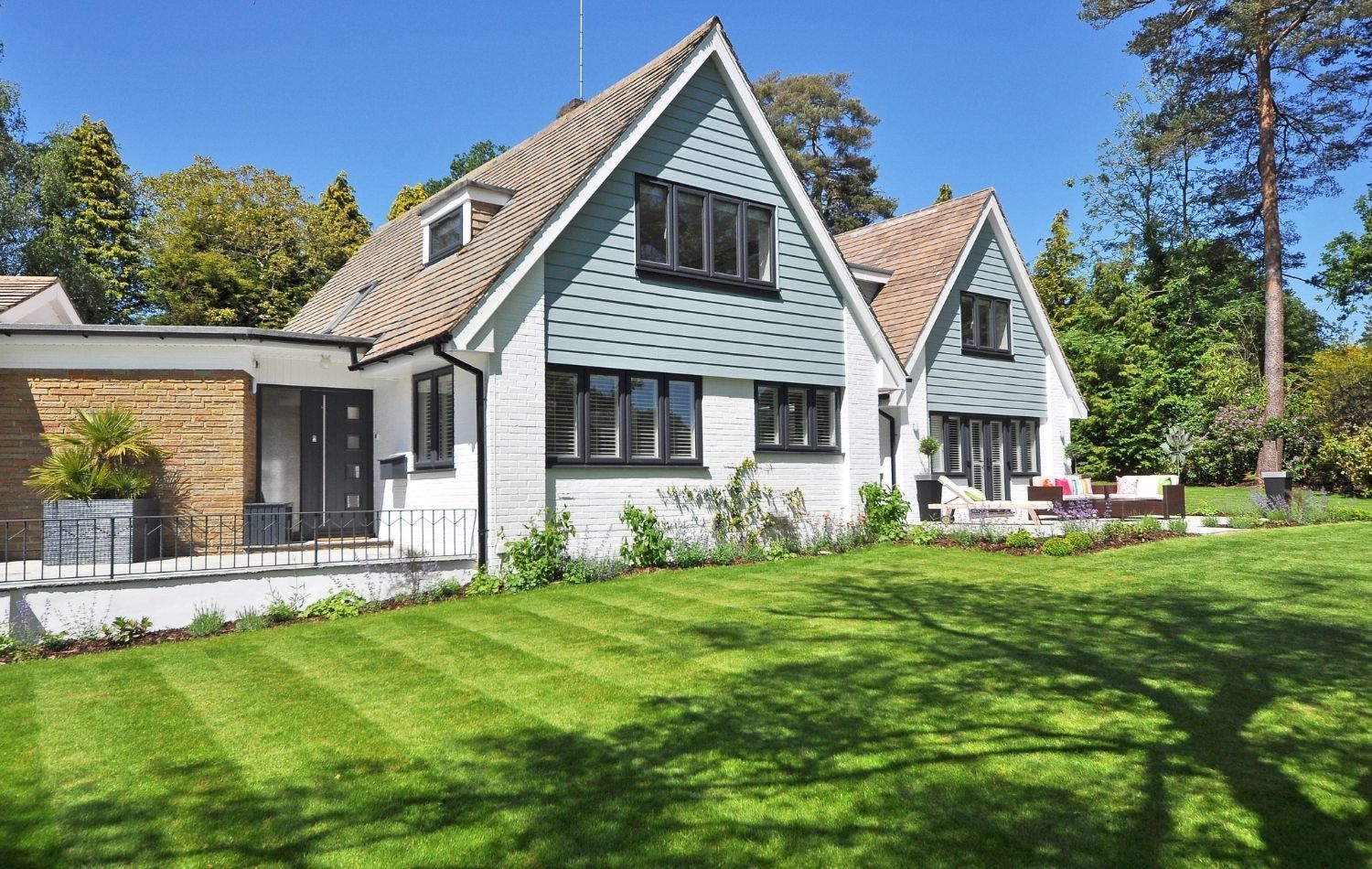 Exterior of a motel; two-story building with blue trim and doors, white siding, blue sky.