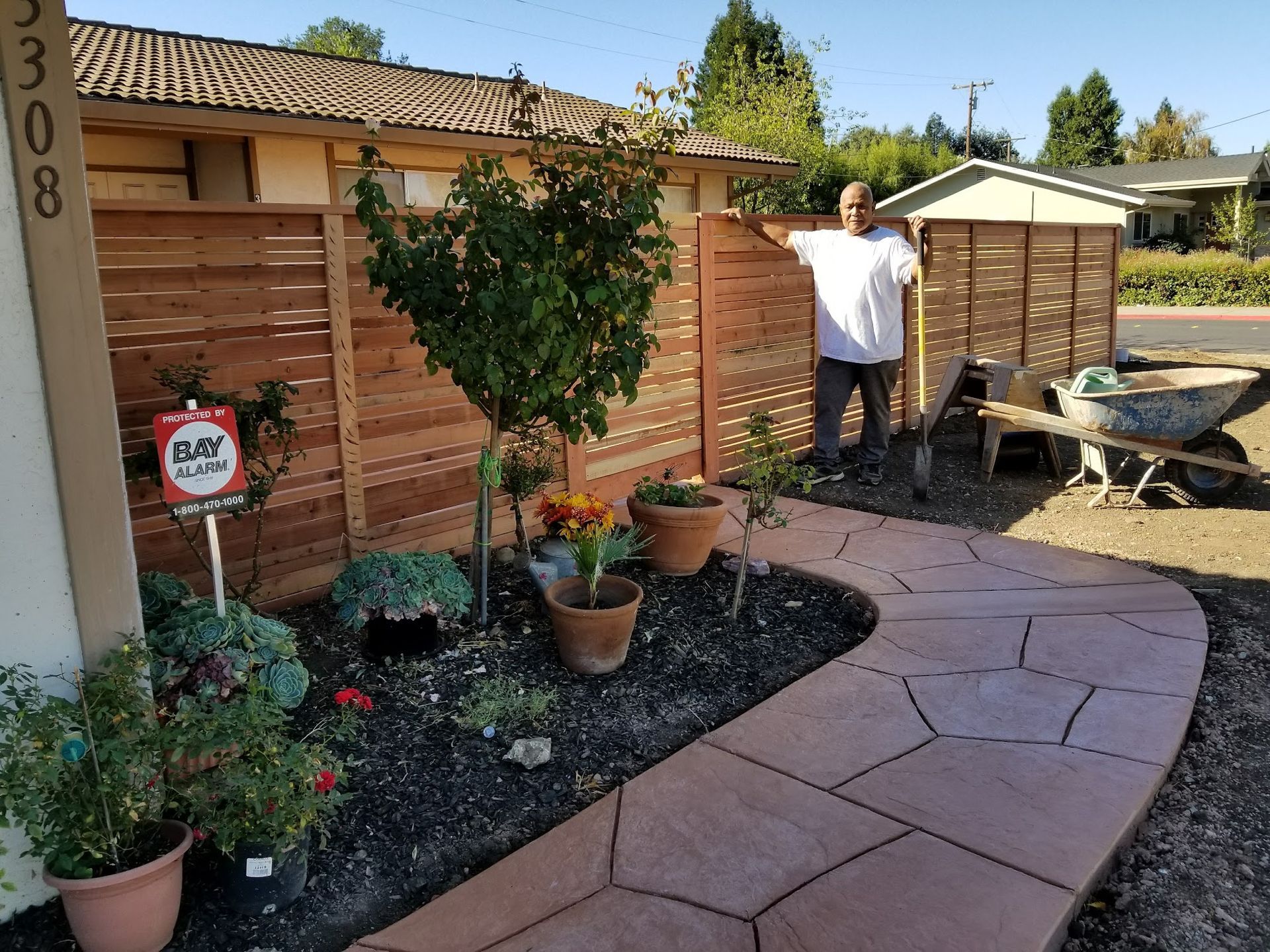 A man is standing on a sidewalk in front of a house