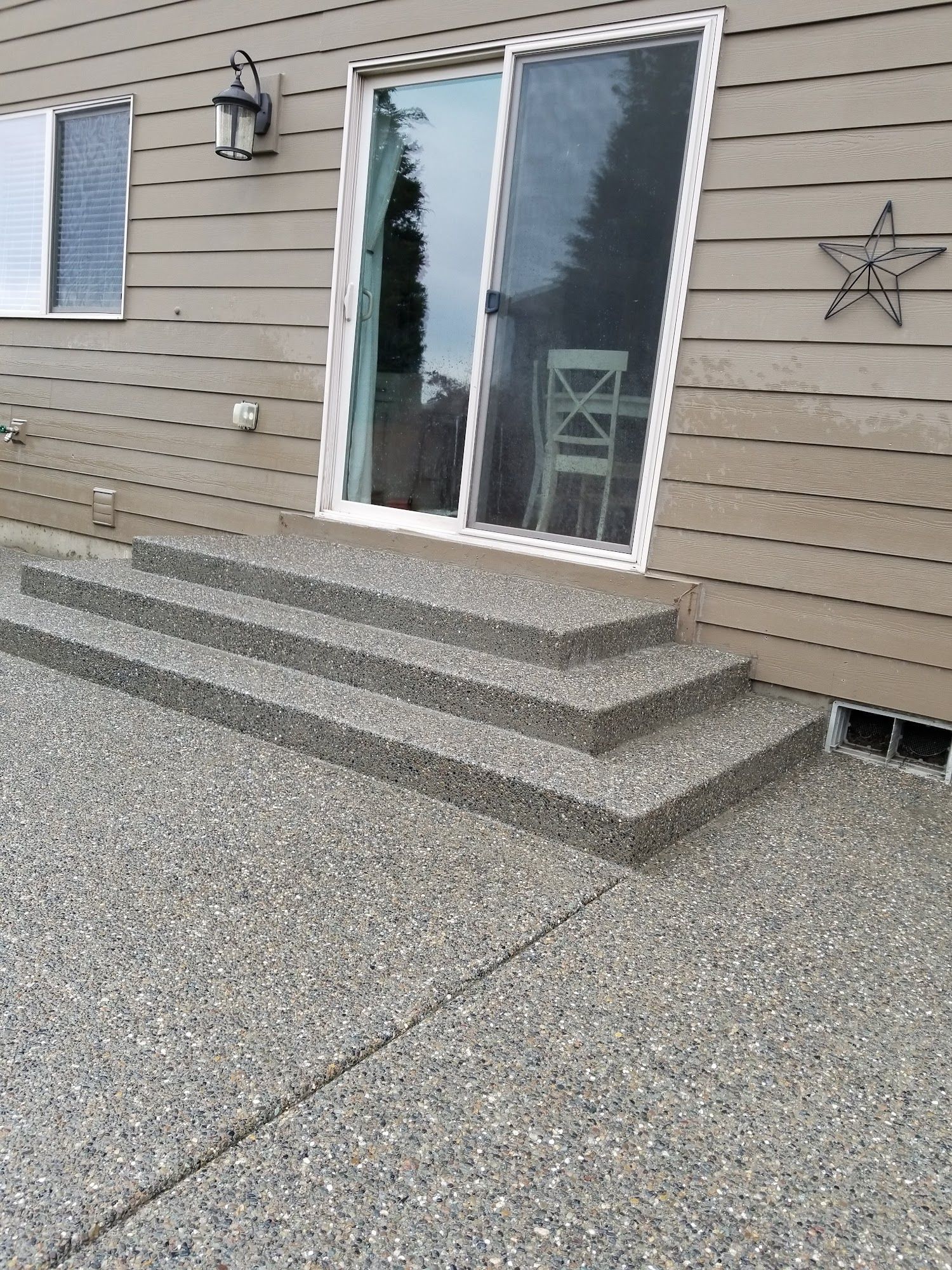 A concrete patio with stairs leading up to a sliding glass door.