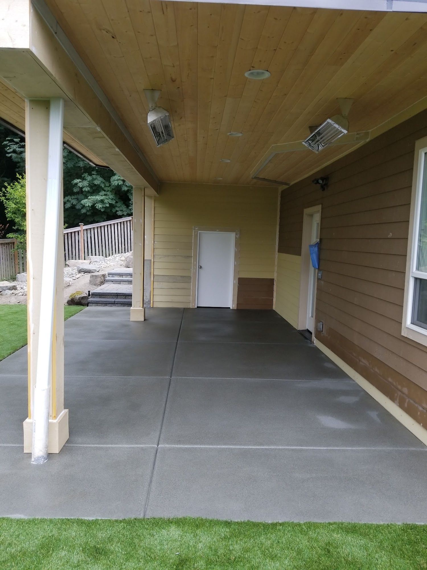 A covered porch with a wooden ceiling and a white door.