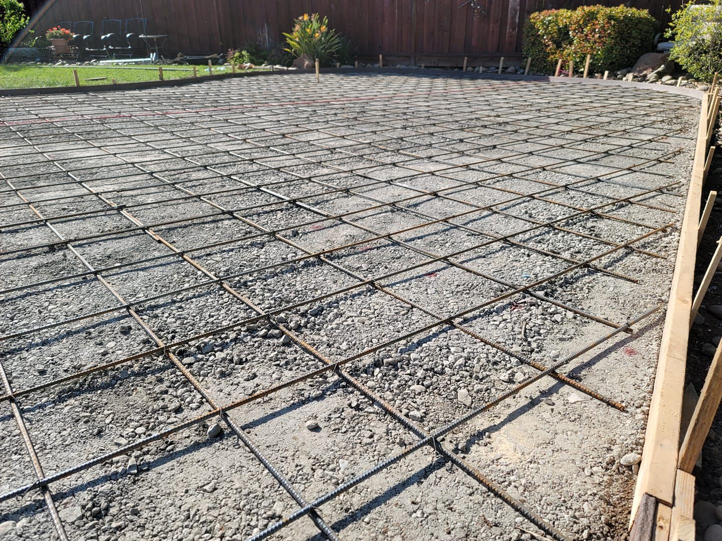A concrete driveway under construction with a fence in the background.