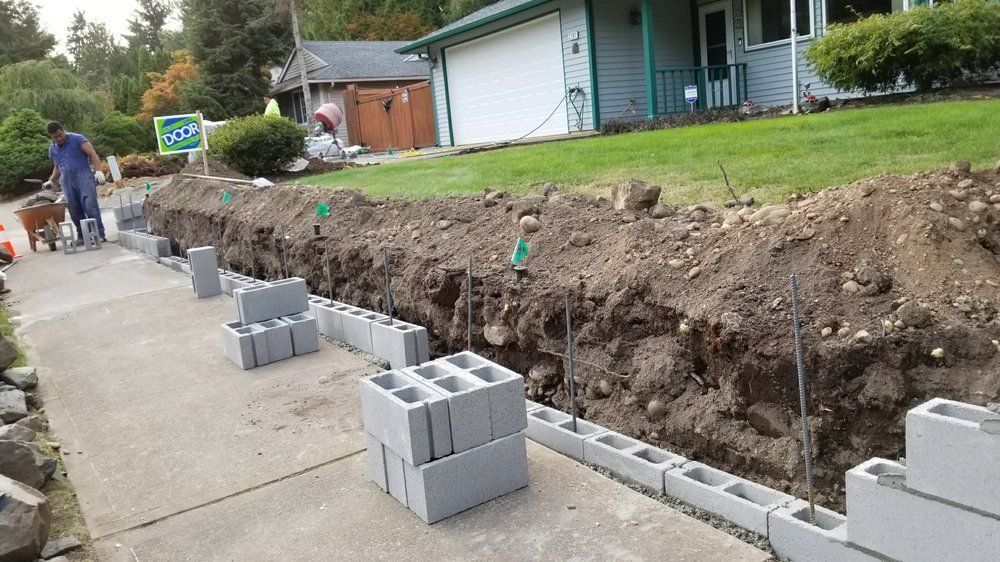 A concrete block wall is being built in front of a house.