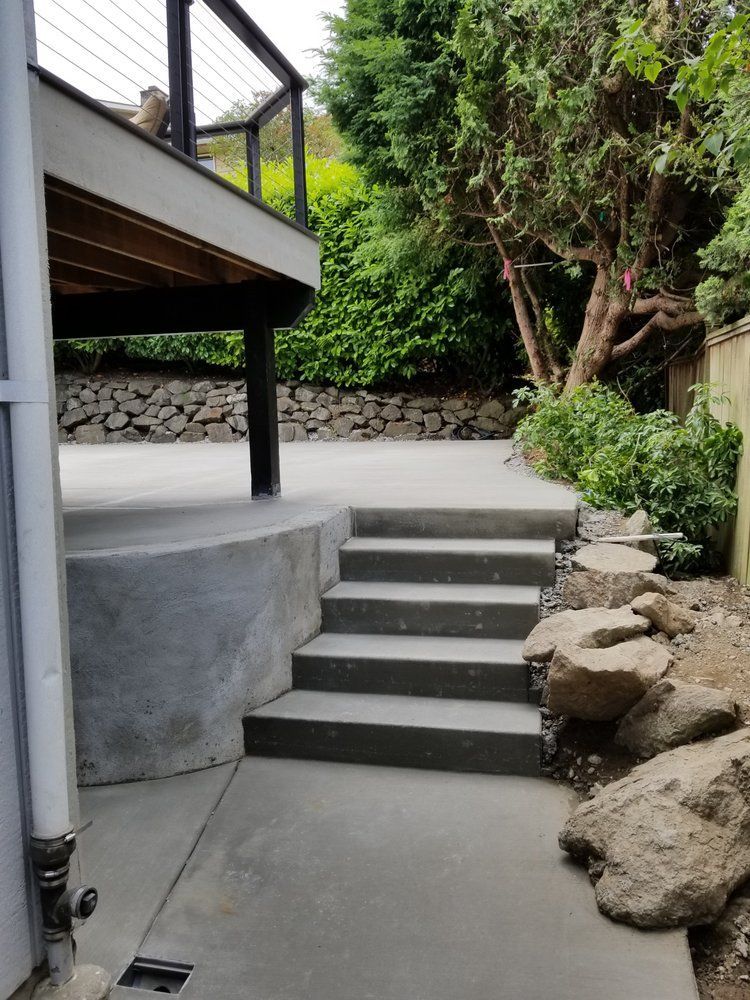 A concrete walkway with stairs leading up to a deck.
