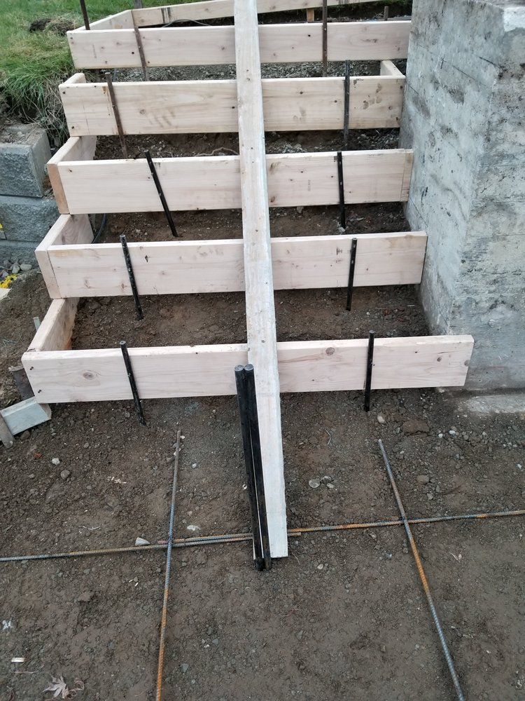 A wooden staircase is being built next to a concrete wall.