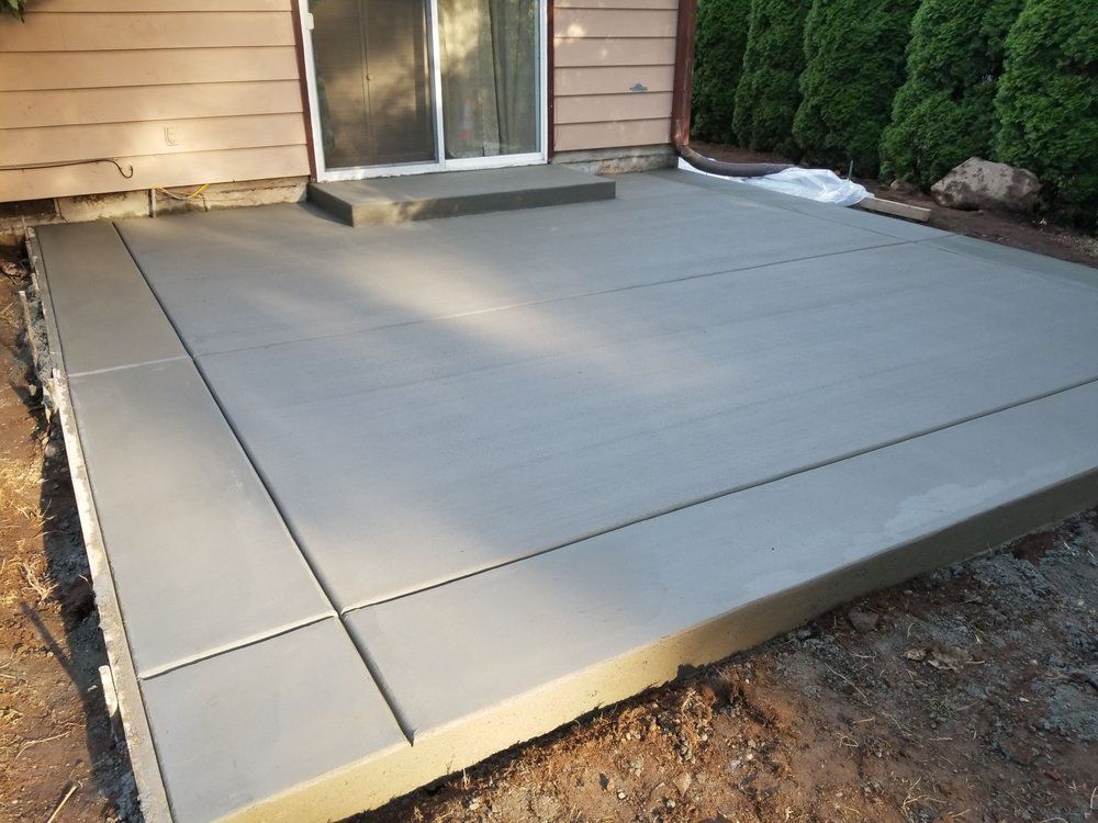 A concrete patio is being built in front of a house.
