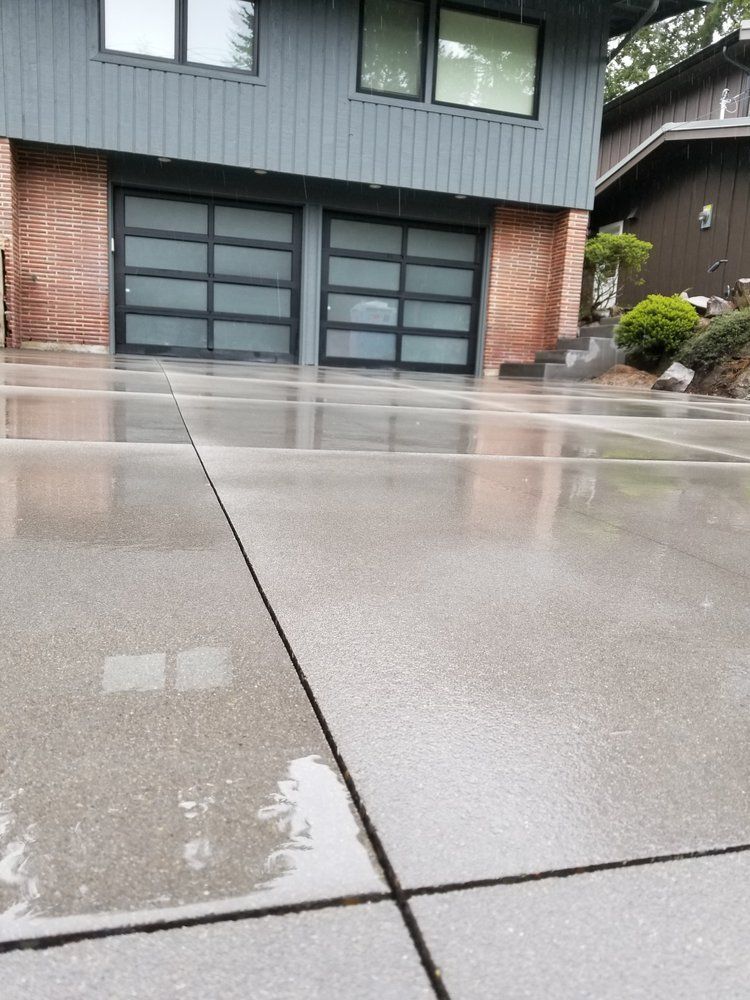 A concrete driveway in front of a house with a garage door.
