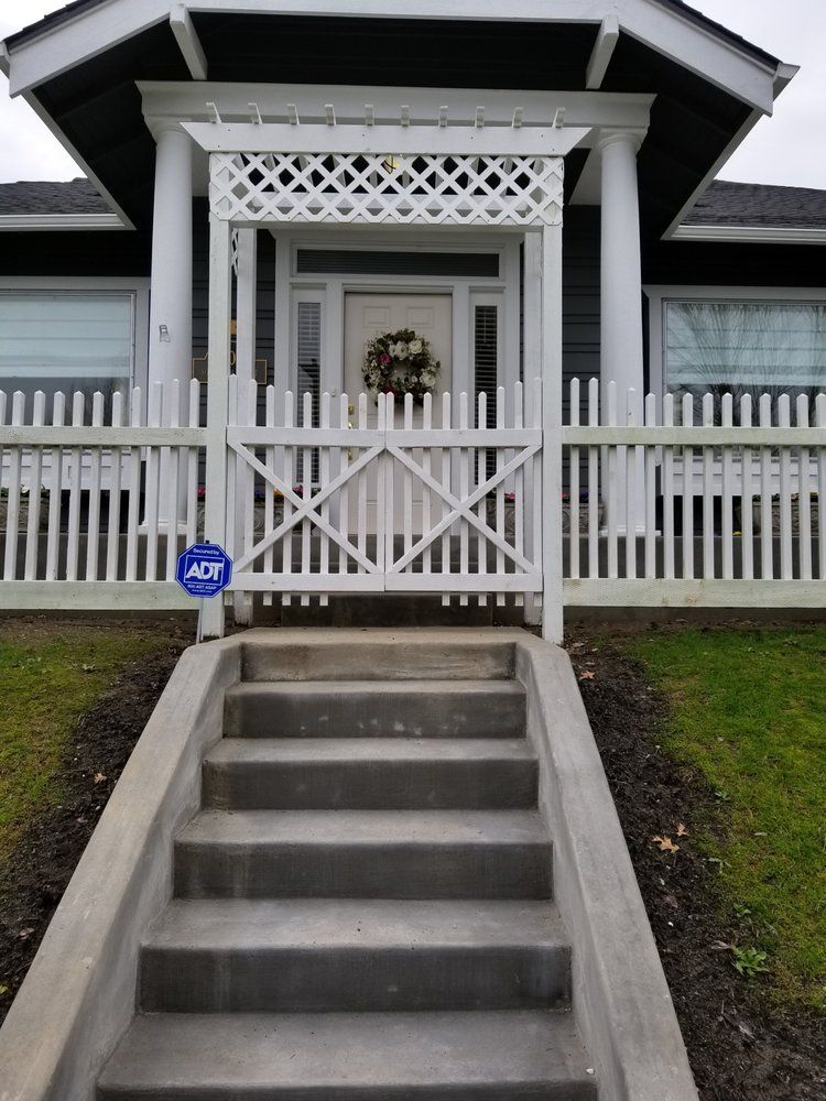 The front of a house with a white picket fence and stairs