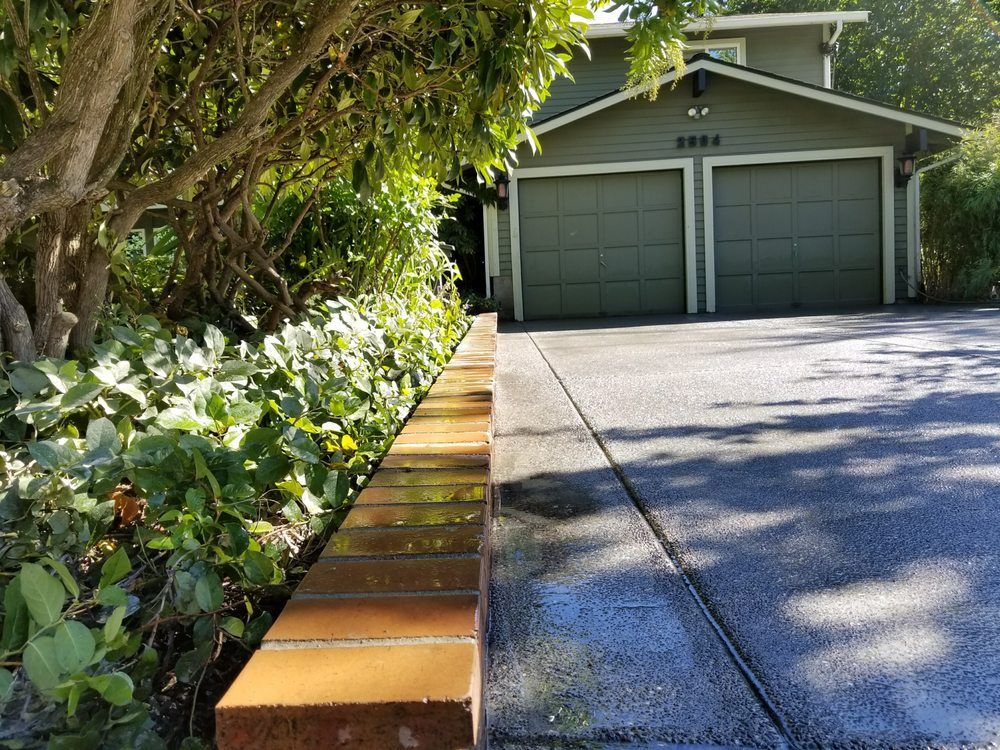 A driveway with a brick wall and a garage in the background