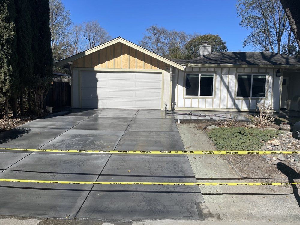 A white house with a concrete driveway in front of it.