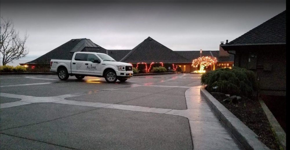A white truck is parked in a parking lot in front of a building.