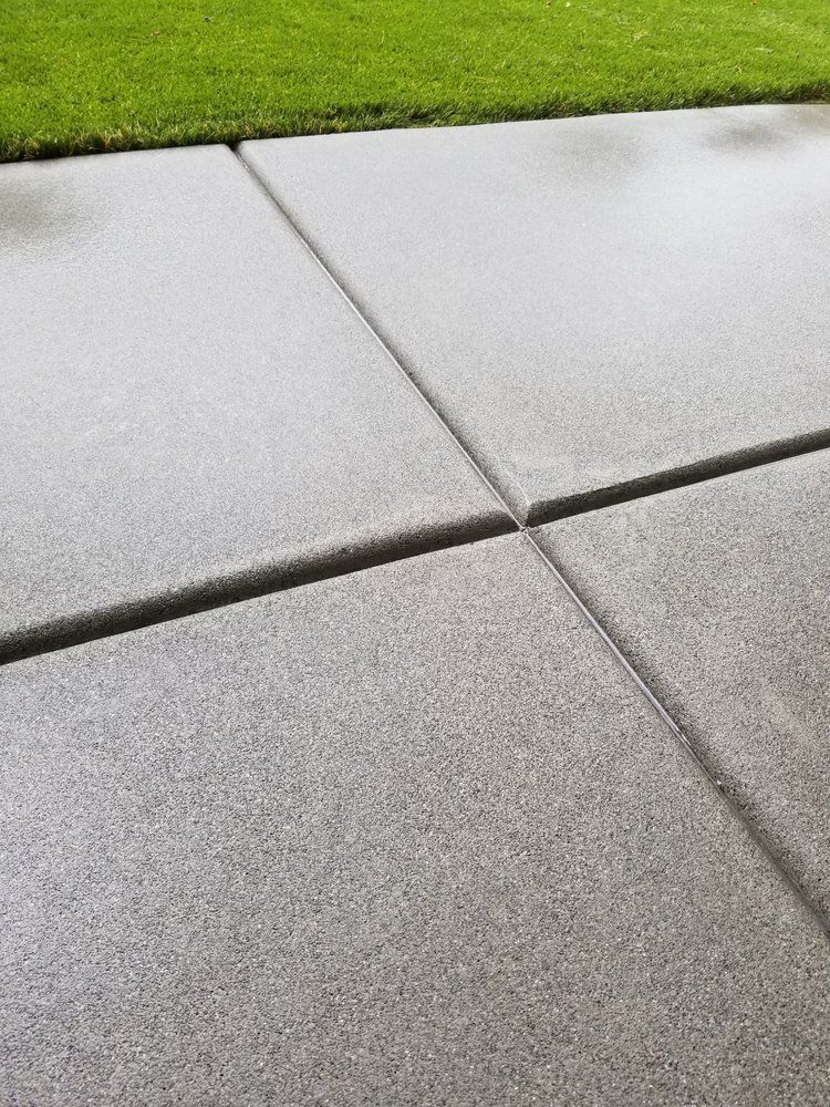 A close up of a concrete driveway with grass in the background.