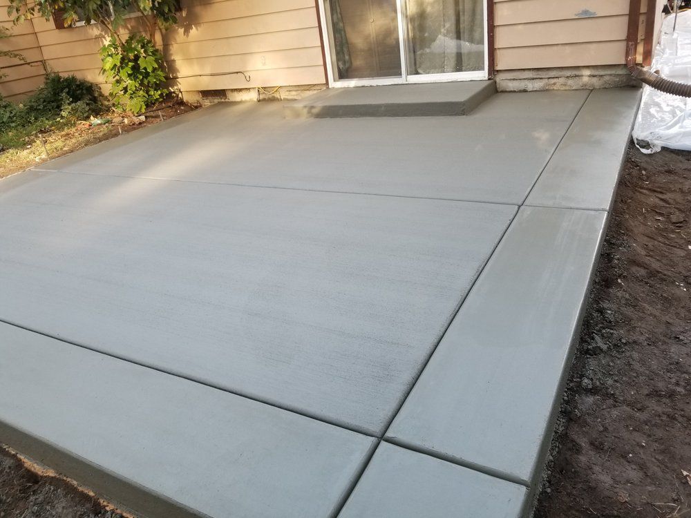 A concrete patio in front of a house with a sliding glass door.
