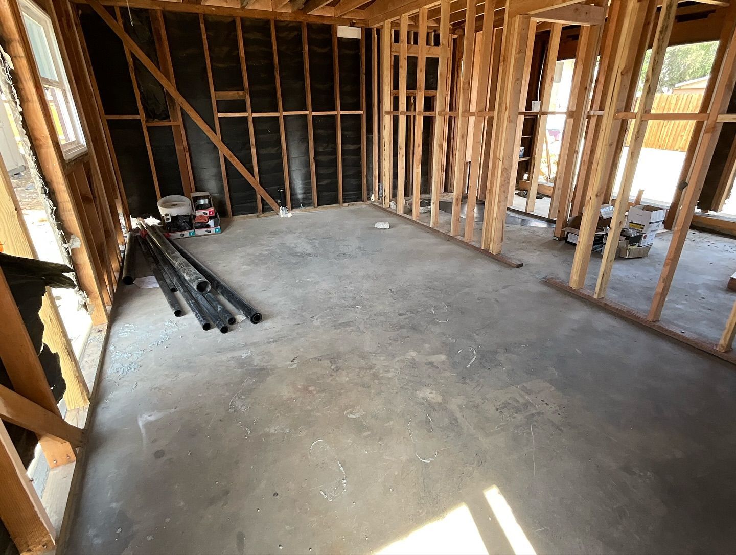 Interior view of a room under construction with exposed wooden framing and a concrete floor.