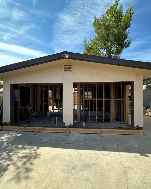 Two-car garage under construction, with exposed wooden frame and concrete floor, set against blue sky.