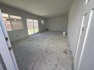 Empty room with white walls, unfinished concrete floor, sliding glass door, and window.