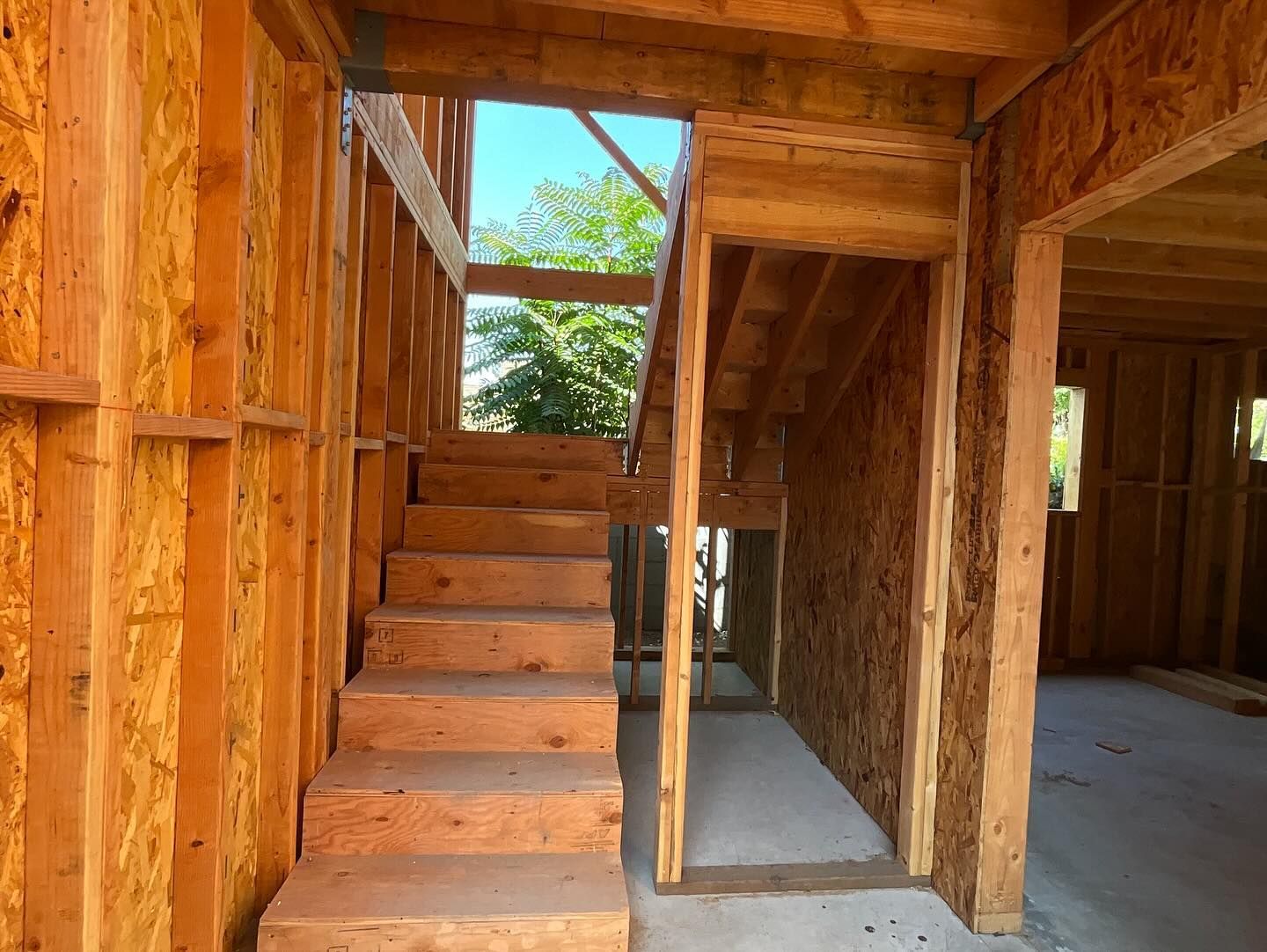 Wooden staircase under construction inside a building. Daylight shines from the top.