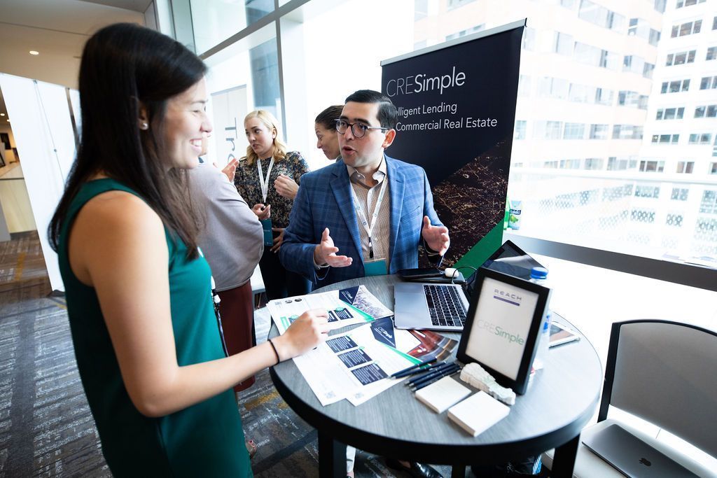A woman is standing at a table talking to a man at a job fair.