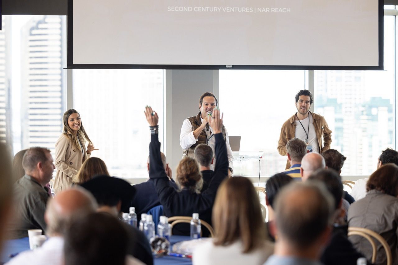 A group of people are sitting in a room with their hands up.