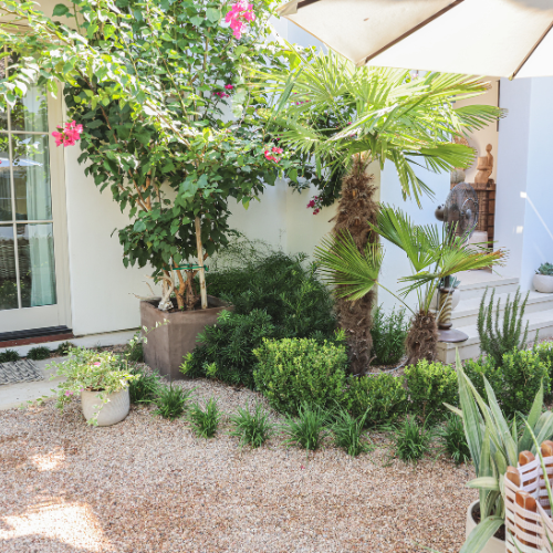A lush green lawn is surrounded by gravel and a walkway.