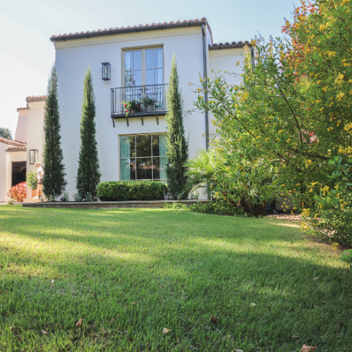 A lush green lawn is surrounded by gravel and a walkway.