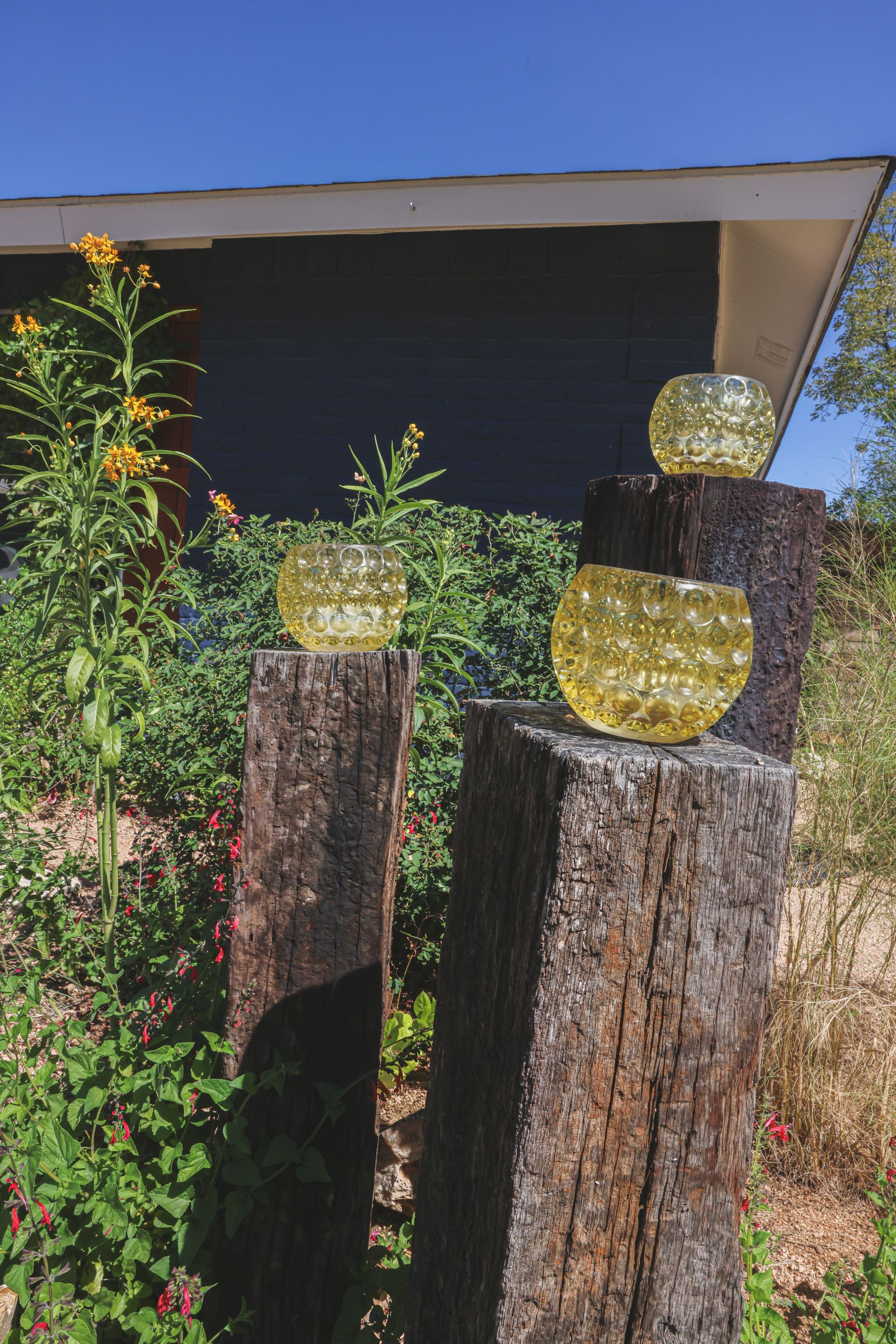 Three glass balls are sitting on a wooden post in front of a house.
