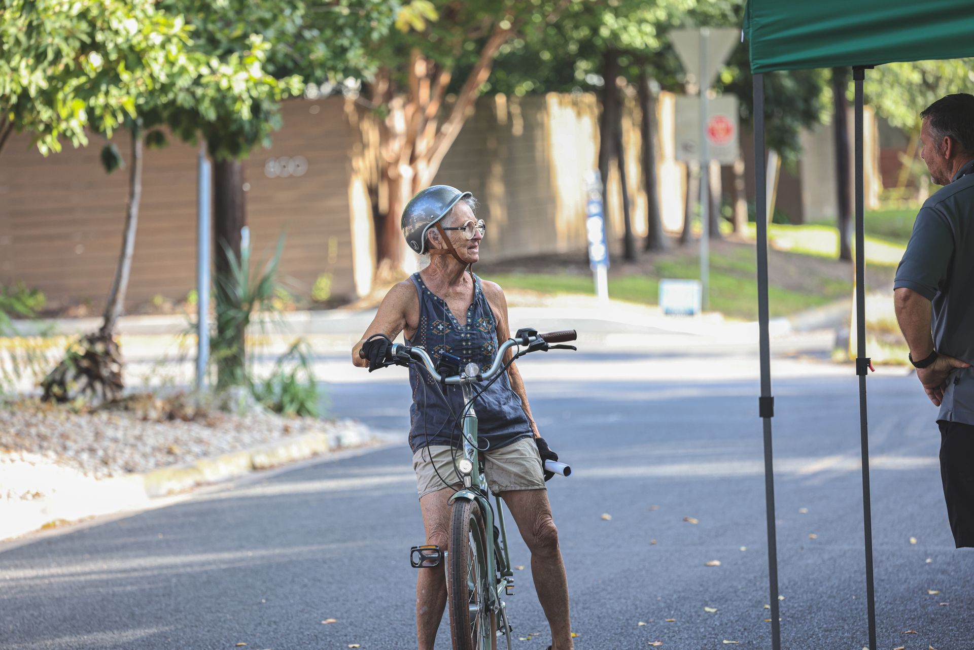 An older woman is riding a bike down a street.