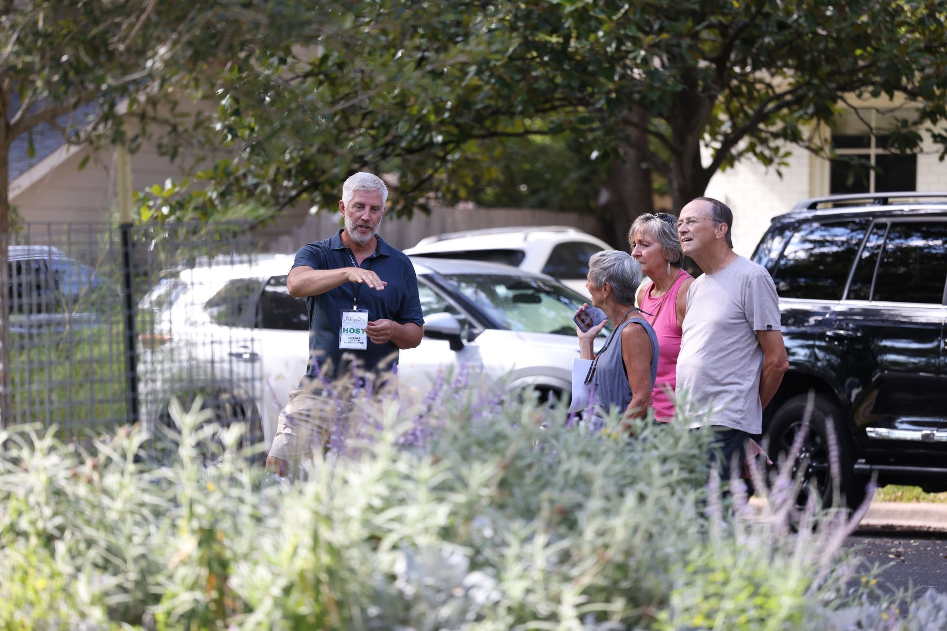 A group of people are standing in front of a car in a parking lot.