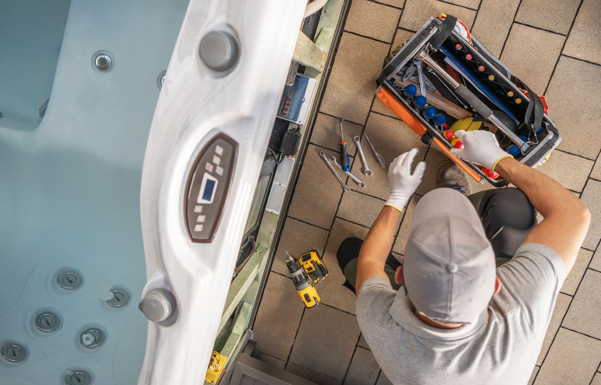 A man is working on a hot tub with a toolbox.