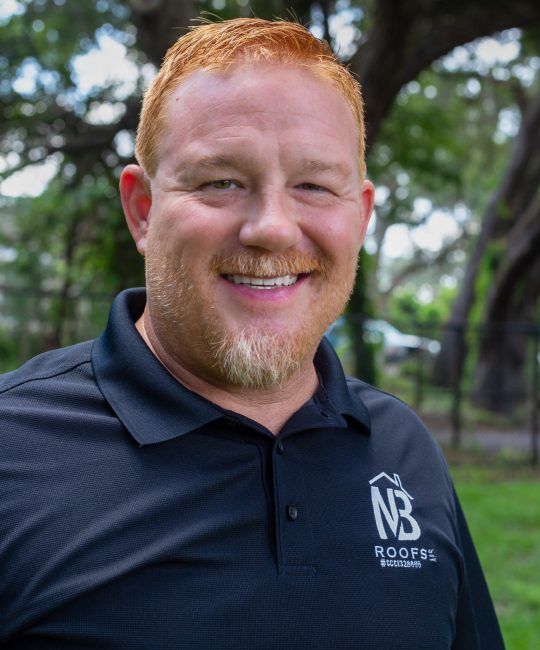 Our team  Scott Washburn with red hair and a beard is wearing a black shirt that says nb roofing