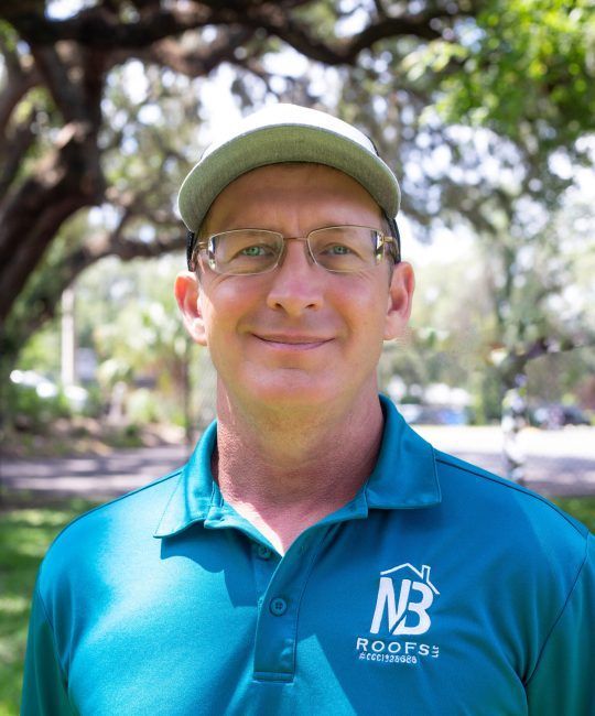 One of our team Aaron Baker, wearing a hat and glasses is wearing a NB roofing shirt