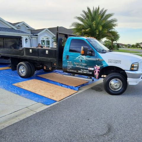 A blue and white painted company service truck is parked in front of a house