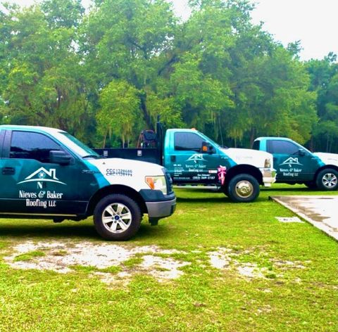 Three company service trucks are parked in a grassy area 