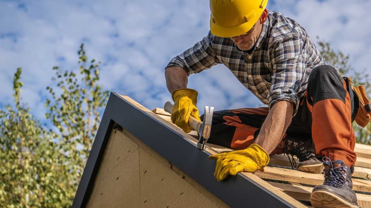 A worker in protective gear fixing a roof.