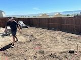A man is walking through a dirt field in a backyard.