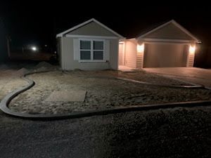 A house is lit up at night with a hose in front of it.