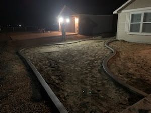 A house is being built at night with a lot of dirt in front of it.